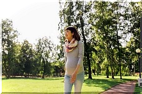 A pregnant woman with a belly band walks in the park