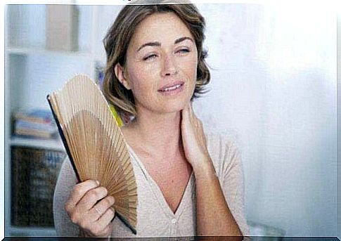 A woman uses a fan for hot flashes