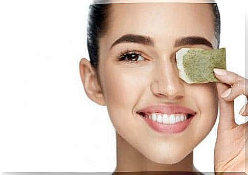 Woman holds a tea bag on her eye